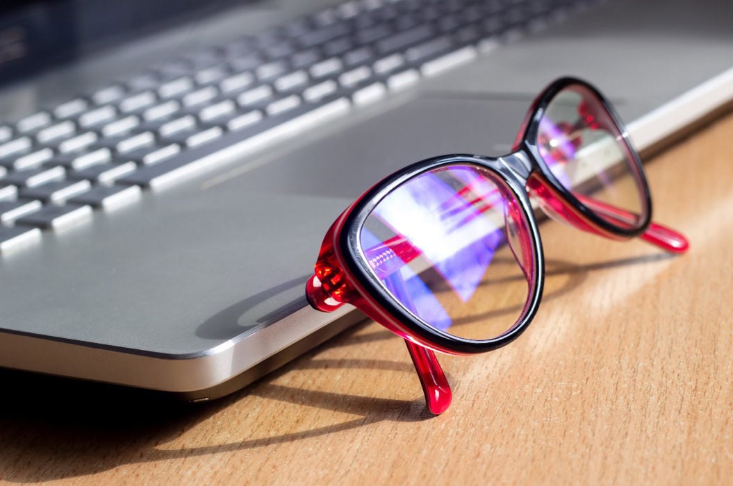 Rote und schwarze Damenbrille für die Arbeit am Computer mit Blaufiltergläsern in der Nähe des Laptops.